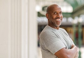 Man in gray shirt smiling outside
