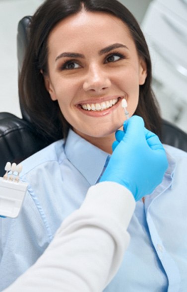 a dentist matching the shade of a patient’s tooth