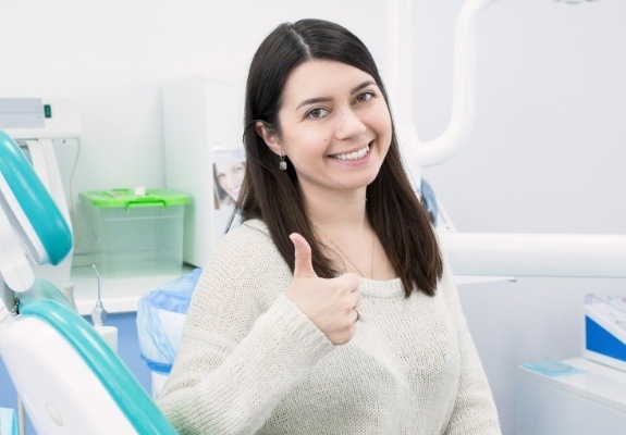 Young woman giving thumbs up after tooth extractions