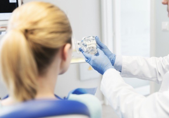 Dentist and patient looking at model smile during dental checkup and teeth cleaning