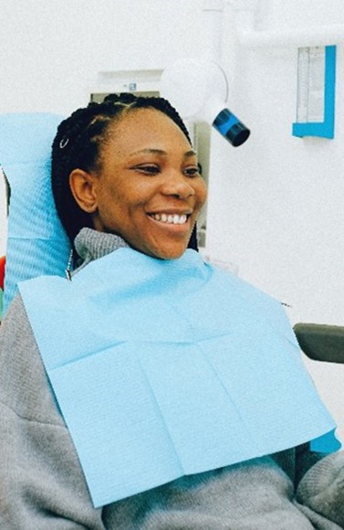 Smiling female patient looking in dental mirror