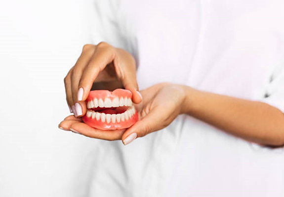 a closeup of a patient holding dentures in Lewisville, TX