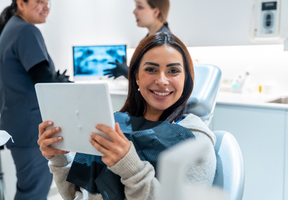 Woman smiling while holding mirror in treatment room