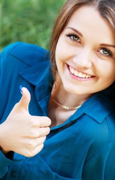 Smiling woman giving thumbs up after periodontal disease treatment