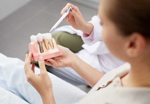 Dentist and dentistry patient looking at dental implant smile model