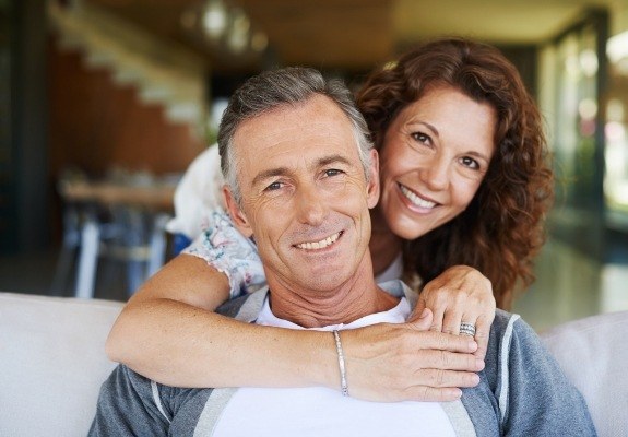 Smiling man and woman enjoying the benefits of dental implants