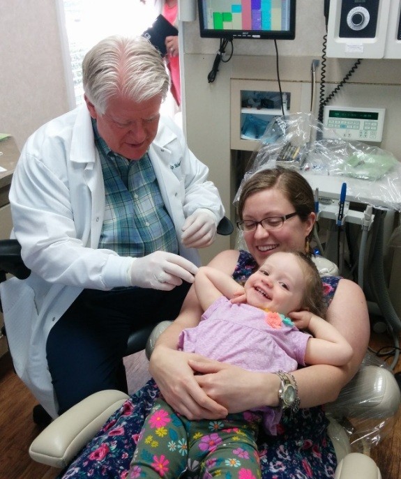 Doctor Sehnert talking to mother and child in dental treatment room