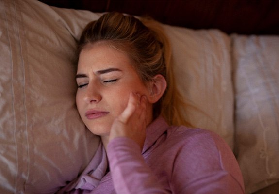 Woman lying in bed with jaw pain