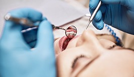 Dentist cleaning a patient’s teeth with small mirror and pick