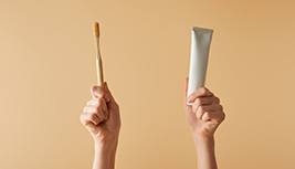 Hands holding up a toothbrush and toothpaste