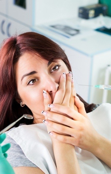 Fearful patient in need of sedation dentistry covering her mouth