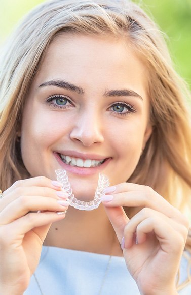 patient smiling while holding SureSmile in Lewisville