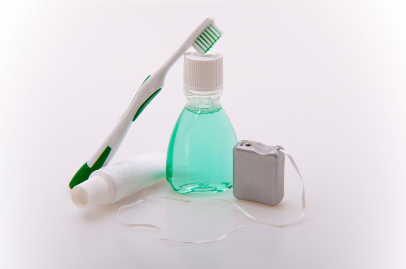 Toothbrush, toothpaste, travel-size mouthwash, and floss, respectively