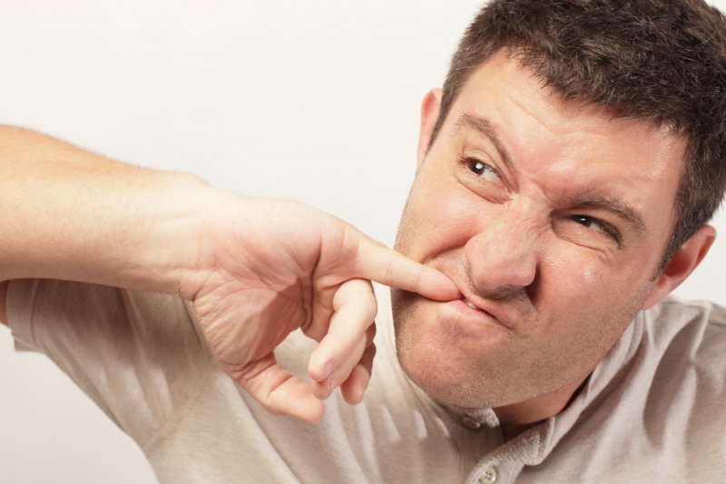 A man trying to dislodge something stuck between his teeth