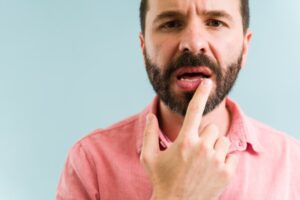 Man pointing at his dry mouth. 