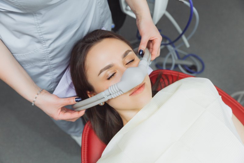 A dentist placing a sedative mask over a woman’s nose