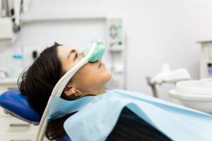 Profile view of woman in dental chair with green nitrous oxide mask over nose